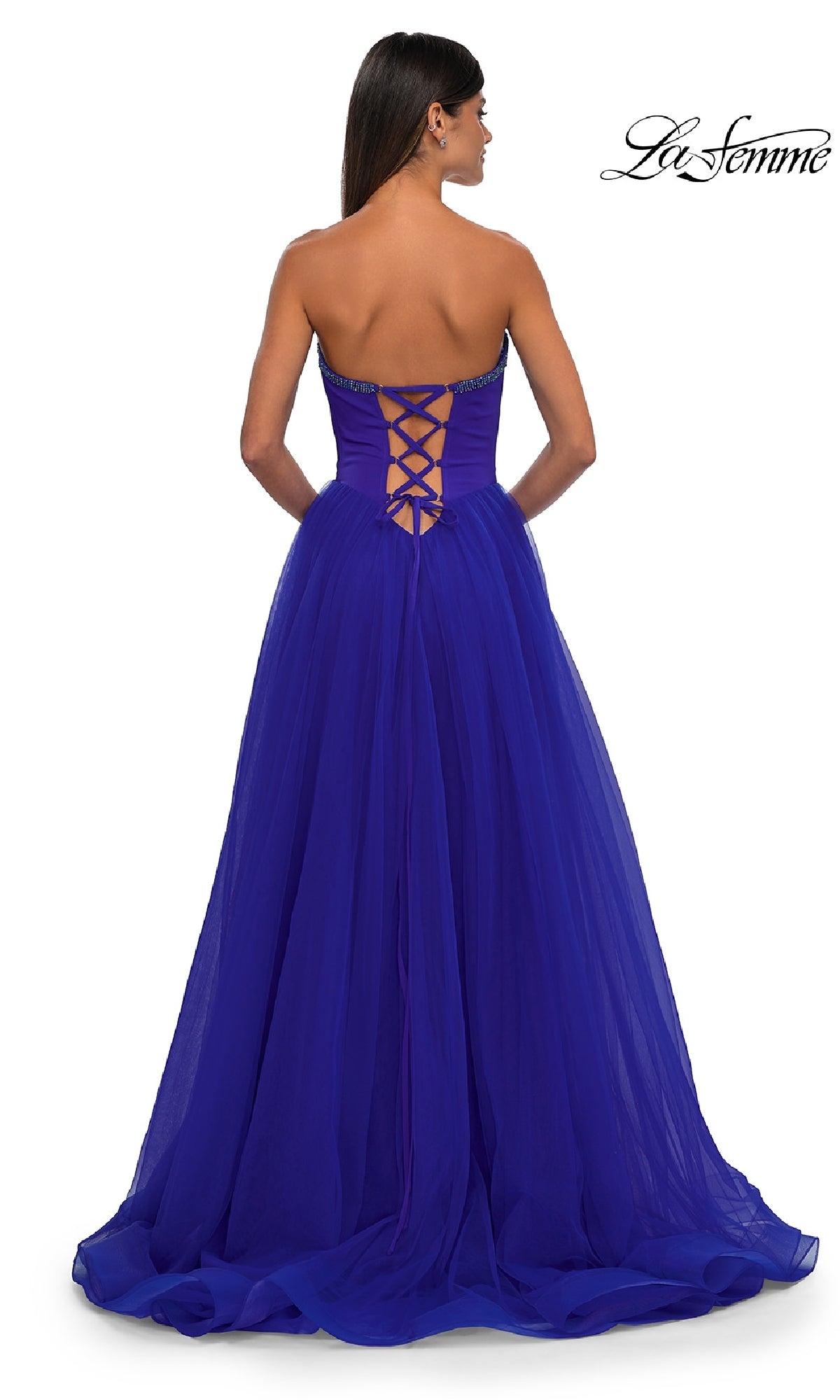 A woman faces away in a royal blue, strapless sweetheart La Femme 32731 prom ball gown with a lace-up back and floor-length skirt.